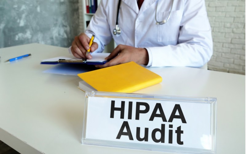 HIPAA-audit A doctor sitting at a table with a HIPAA audit sign